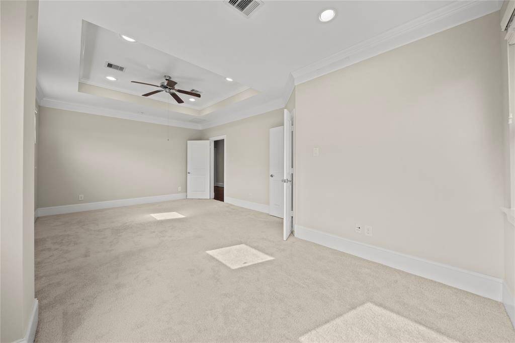 Large primary bedroom with elegant ceiling fan and custom trim.