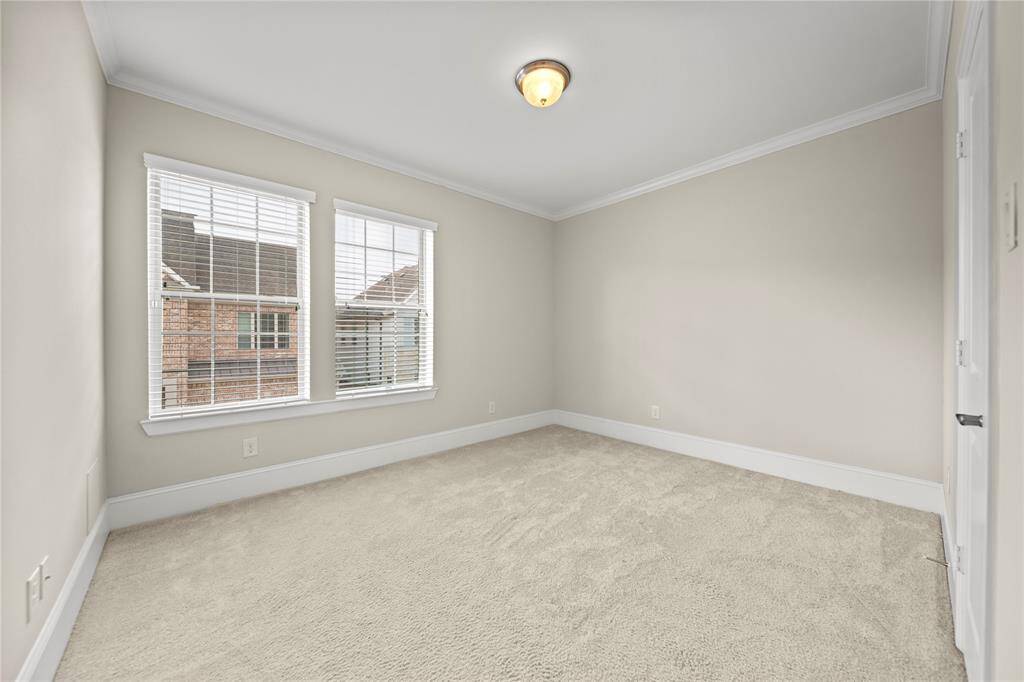 Cozy secondary bedroom with soft carpet and large windows.