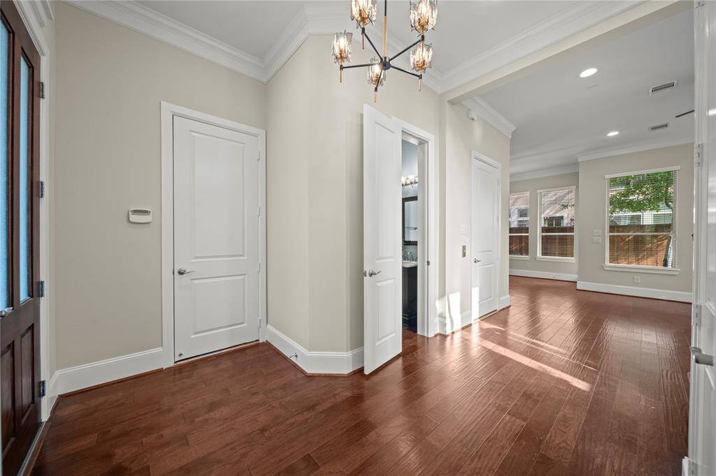 Grand entry hallway with gleaming hardwood floors and modern chandelier.