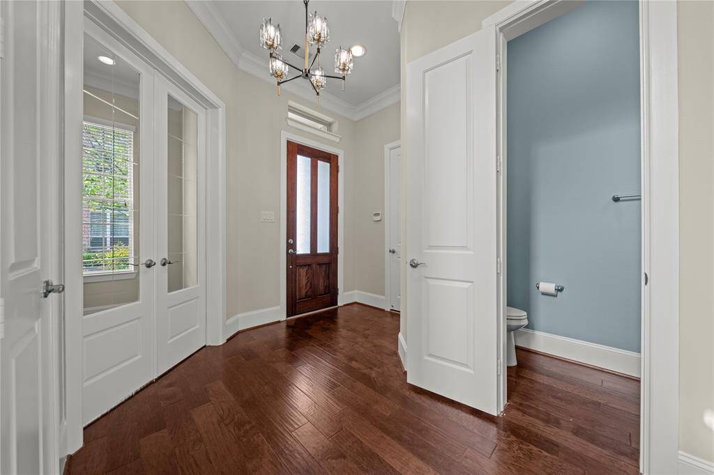 Grand entry hallway with gleaming hardwood floors and modern chandelier.