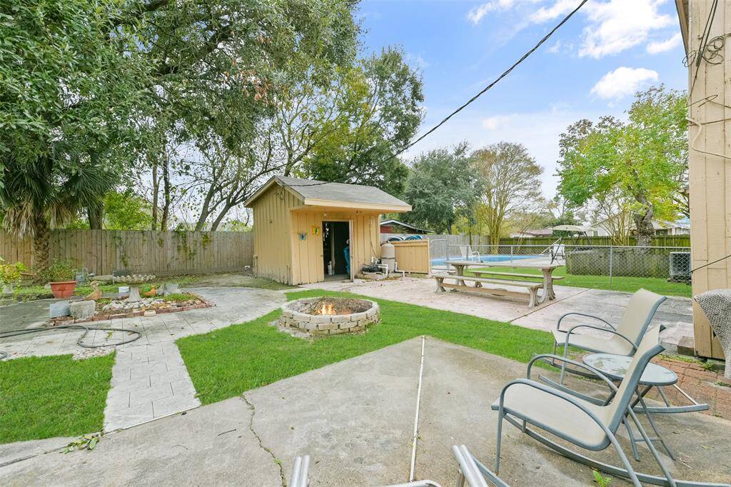 Enjoy this spacious outdoor living area with a pool, fire pit and tiled paths.