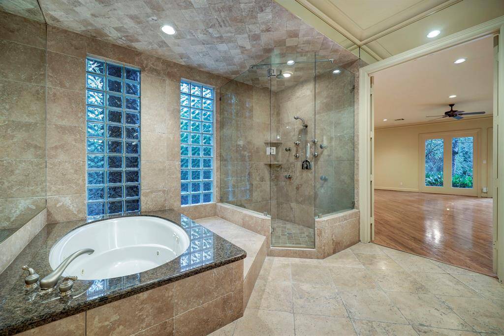 There is a jetted tub set in granite slab surround with travertine and great shower with full glass enclosure.