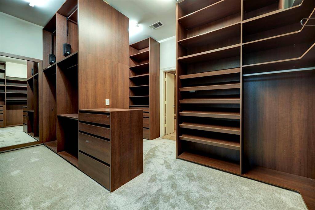 The giant primary closet with extensive built-in shelving and hanging space!