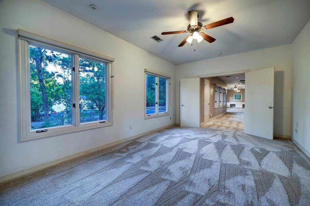 Secondary bedroom 1 with carpet floors and five full-lite windows with custom shades.