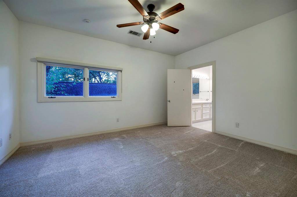 Bedroom 4 with three full-lite windows with custom shades and carpet floors.