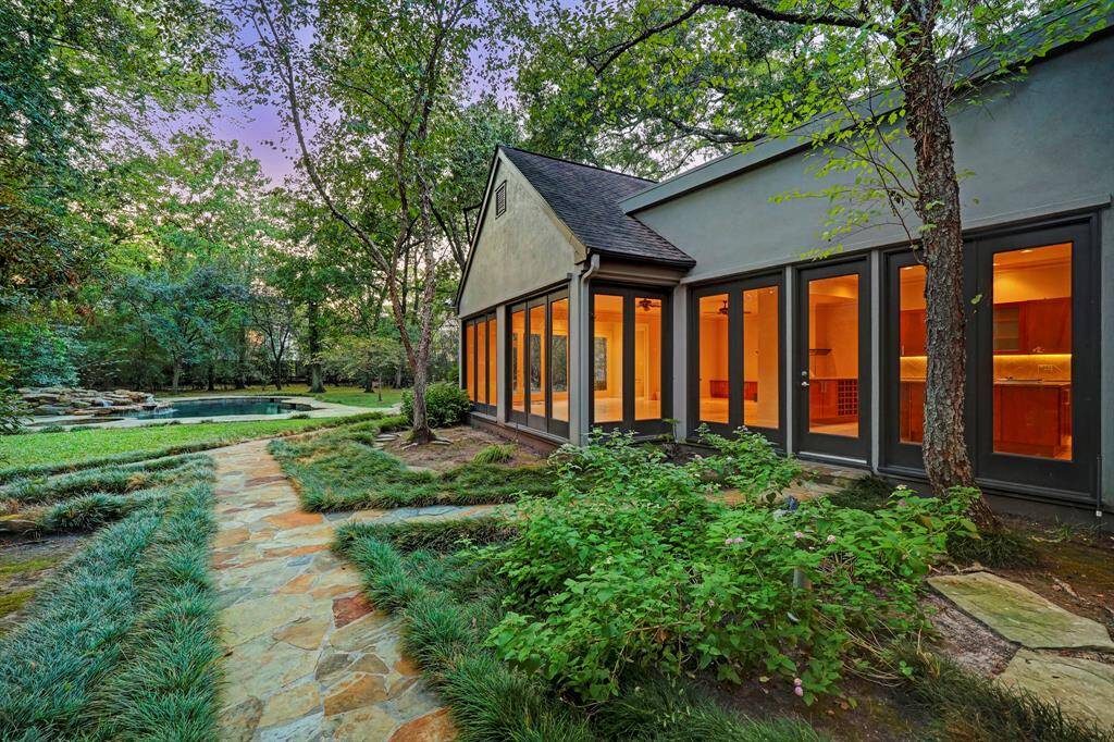 A lovely path leading from the house to the pool and backyard. The lush green surrounds the home.