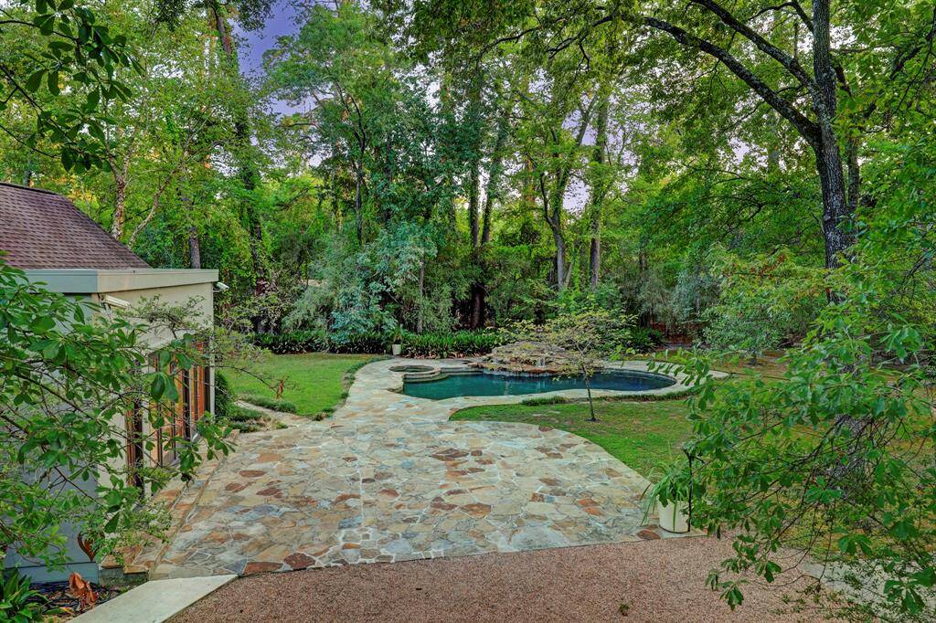 Another view of the large pool and jacuzzi with soaring trees. There is plenty of space for outdoor entertaining.
