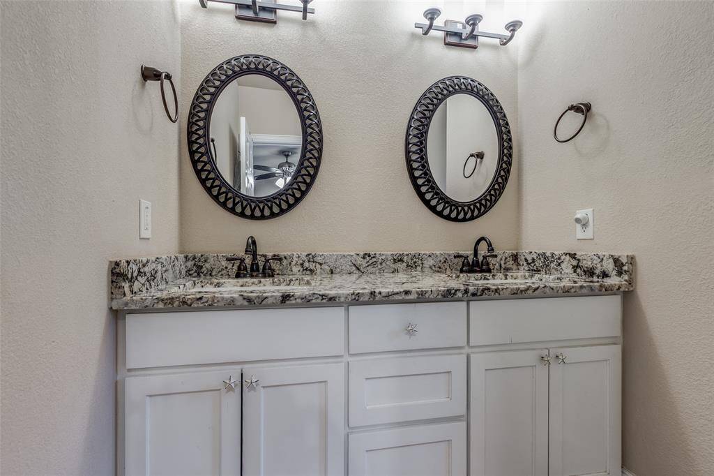 Primary Bathroom with double sinks, framed mirrors, granite countertops, and updated vanity.