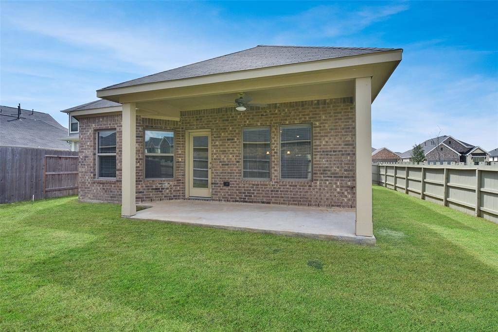 Backyard with covered patio, brick facade, and wooden fence .