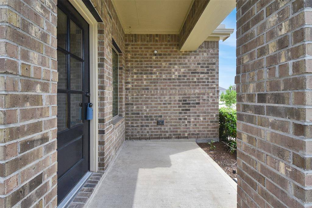 A covered entryway, leading to a house with visible greenery outside.