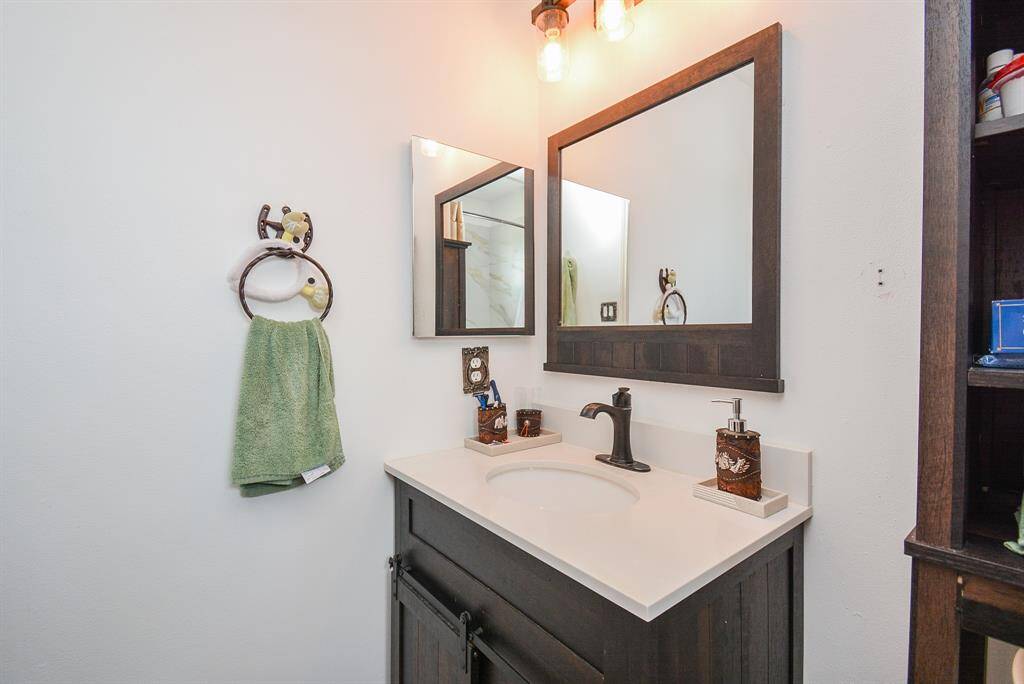 What a lovely, welcoming pale, granite topped ? sink, in nice contrast to dark cabinetry and framed wall mirror.