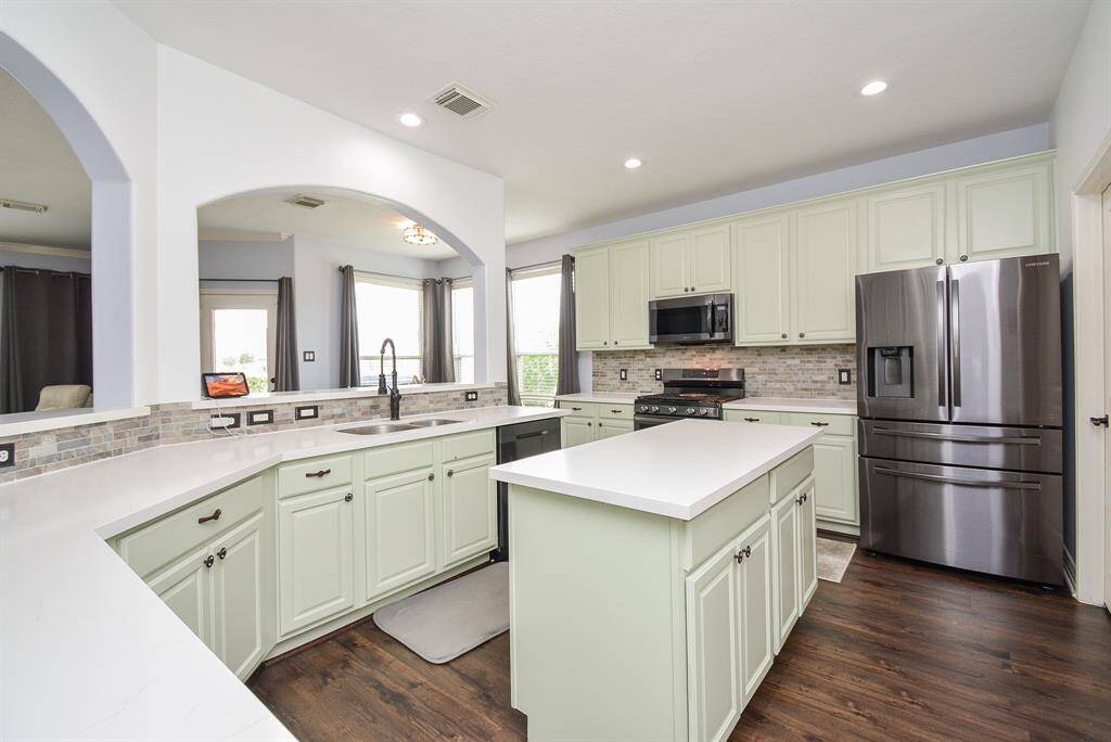 Serene toned cabinetry fills every precious inch of wall and floor space in this exquisite chef's kitchen; with contrasting light/dark themed storage and darker, rustic flooring. Note the gorgeous wall cut-outs (left) that distinguish kitchen/living space.