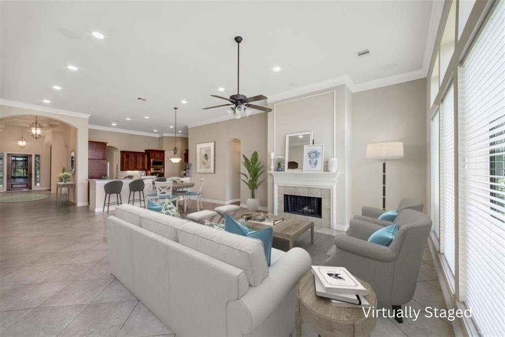 From this angle, you can truly appreciate the spaciousness of the family room, just waiting for family memories to be made. The room exudes warmth, with a charming fireplace featuring wood mantel and tile hearth: perfect for cool evenings. Recessed lighting above adds a touch of elegance, while high ceilings with crown molding add to the room's airy and inviting feel.