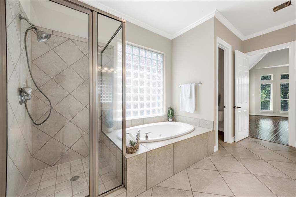 Indulge in relaxation as you soak your worries away in the deep jetted tub, perhaps with a glass of wine in hand. Alternatively, opt for a quick rinse in the separate shower. Take note of the block glass for privacy on the window and enjoy the modern touch of updated plumbing fixtures, adding both style and convenience.