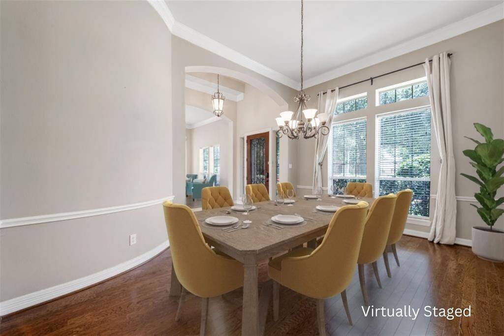 The formal dining area: where cherished meals are shared during holidays and special occasions. Notice the classic charm with chair rail, wood flooring and crown molding. High ceilings give the room an airy feel, while two large windows, complemented by transom windows, flood the room with natural light, creating a warm and inviting atmosphere for gatherings with family and friends.