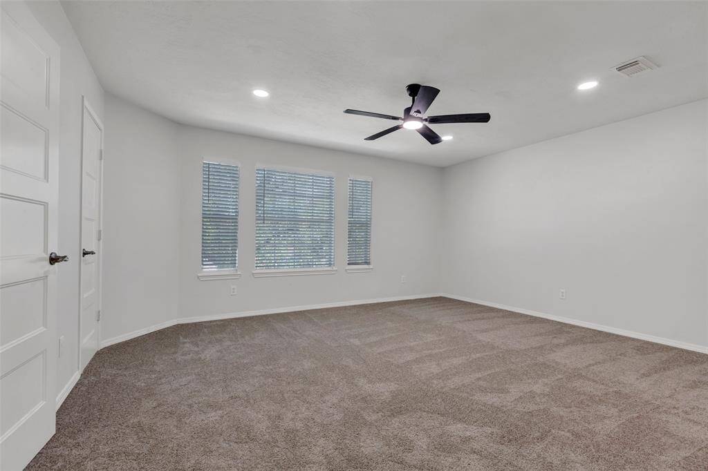 Master Bedroom with a vaulted ceiling, modern ceiling fan, and three large windows for natural light.