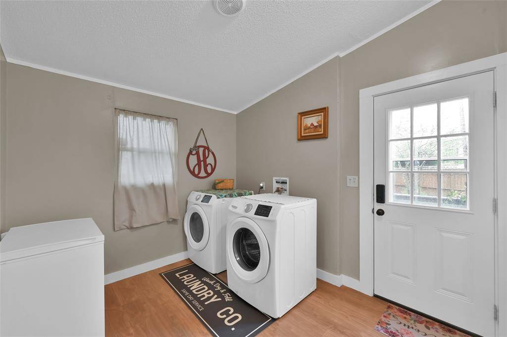 The oversized laundry room has enough space for a second refridgerator, freezer or even extra shelving.  Door leads to fenced in portion of property.