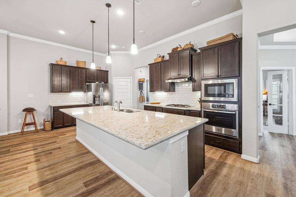 Huge oversized island with quartz countertop. Can easily accomodate four or more barstools.  Rich chocolate cabinets with hardware, subway tile backsplash, extra drawers on lower cabinets make for easy storage, pendant lights, and walk in pantry make this an extra special gourmet kitchen.