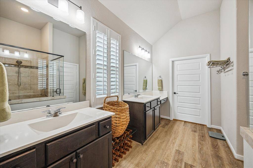 Primary Suite bathroom has two large double sinks, abundance of cabinets, area for laundry basket, make up niche, and even Plantation shutters.  Behind the door is a long oversized walk in closet.