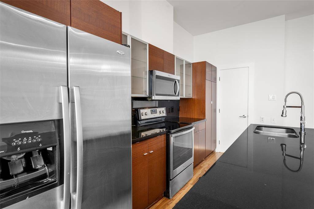Another view of the kitchen and dining area, showcasing the impressive floor-to-ceiling windows with blinds, allowing for abundant natural light while offering privacy and a sleek, modern look.