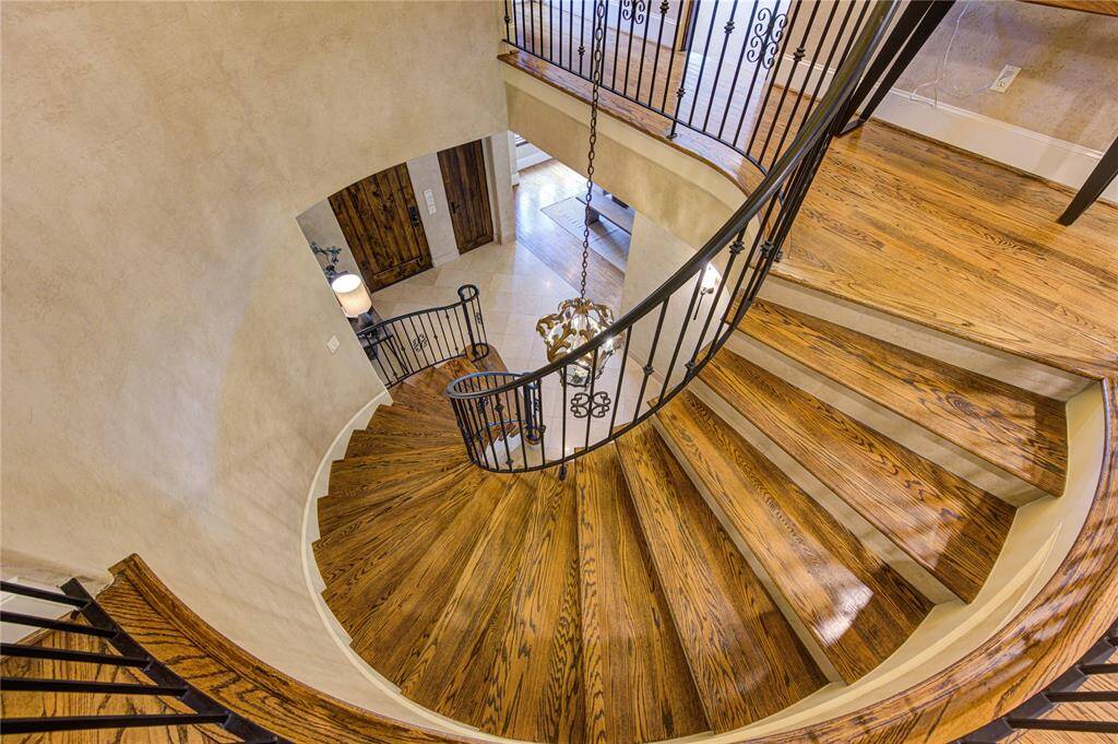 This photo showcases an elegant spiral staircase with polished wood steps and ornate iron railings, offering a grand and stylish focal point in the home.