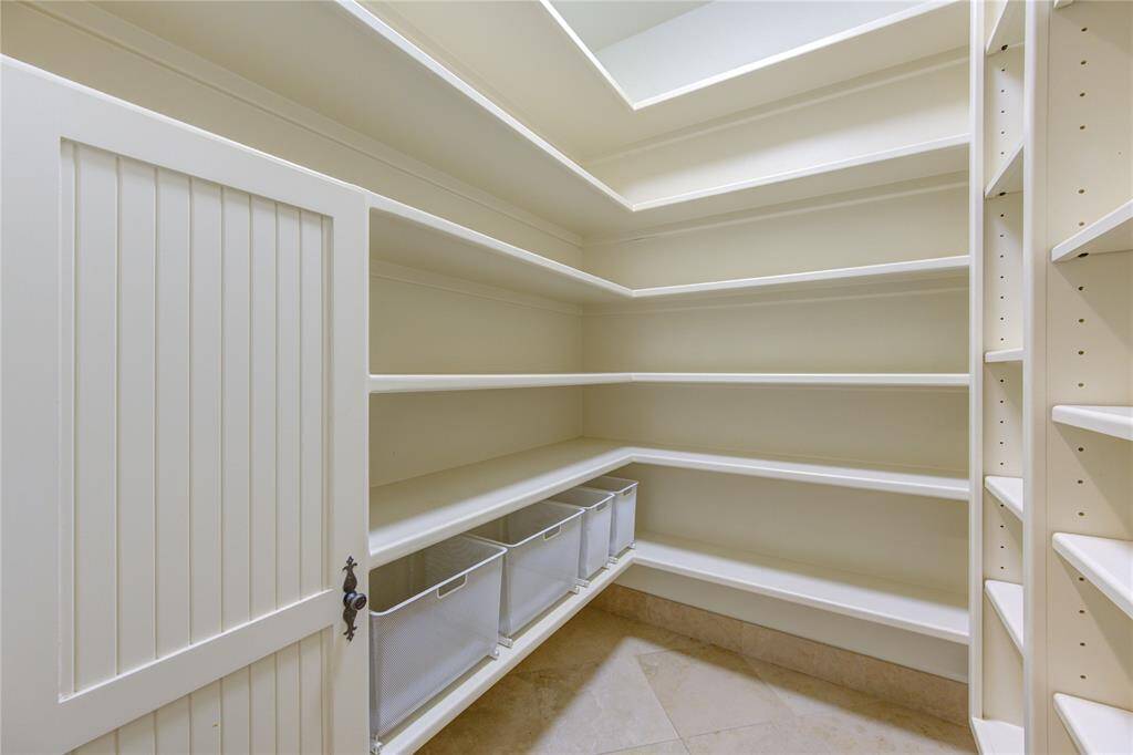 Spacious walk-in pantry with ample shelving and storage bins, perfect for organizing kitchen essentials and groceries.