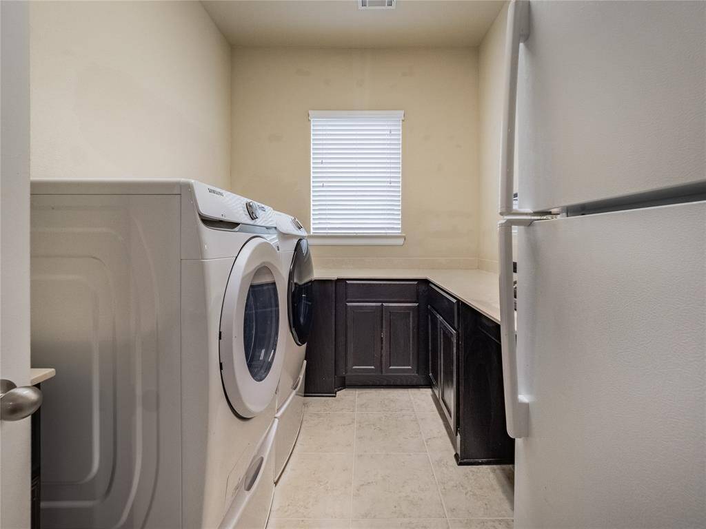 laundry room has cabinets, folding counter top and room for a full size fridge or freezer