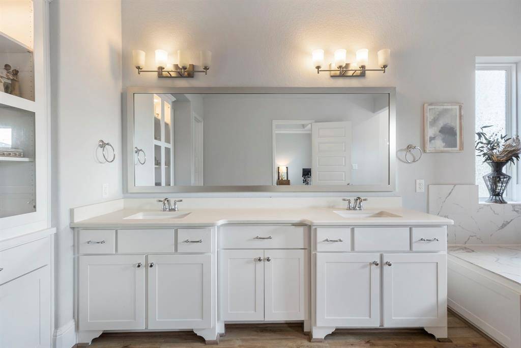 Primary bathroom with double sinks, stunning white quartz countertops, white cabinetry, framed mirror, and built-in storage.