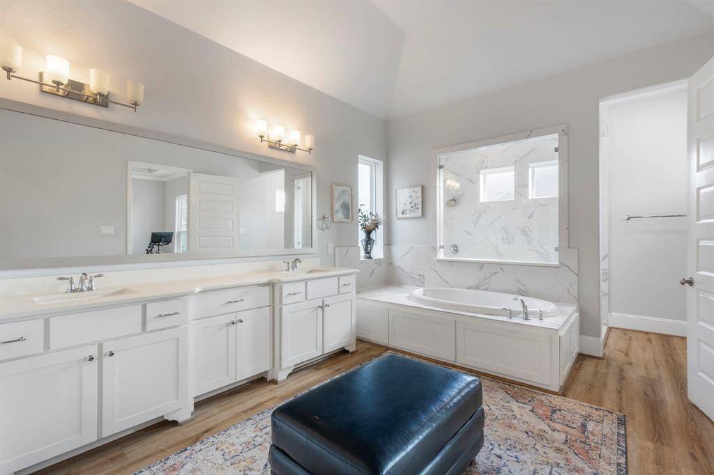 Spacious primary bath comfortably fits an ottoman for both design and function. Seamless flooring transitions throughout the primary suite. Features include a large soaking tub and a generous walk-in shower for true luxury living.