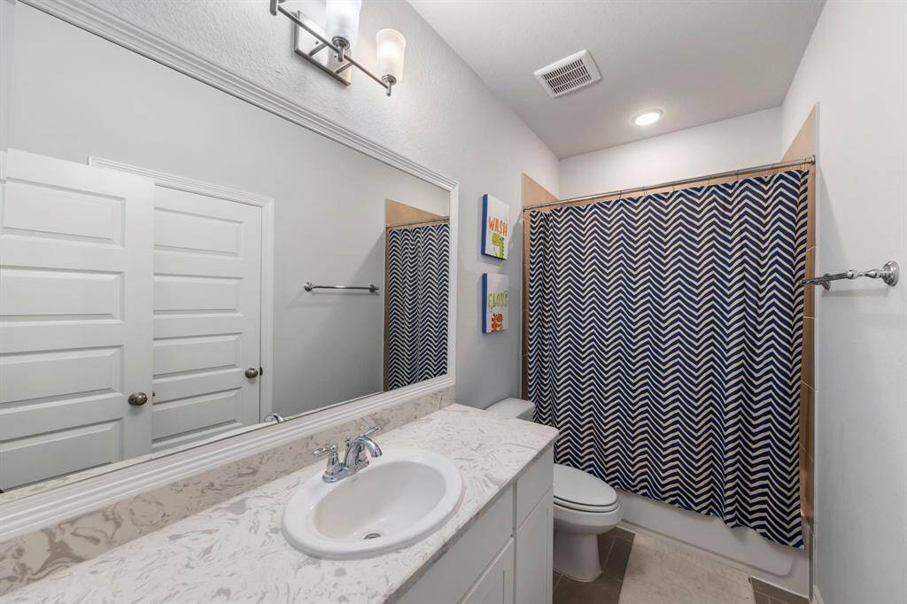 Full bath on the second floor, ideal for common use and an additional upstairs bedroom. Highlights include quartz countertops with ample space, a framed mirror, and tile flooring.