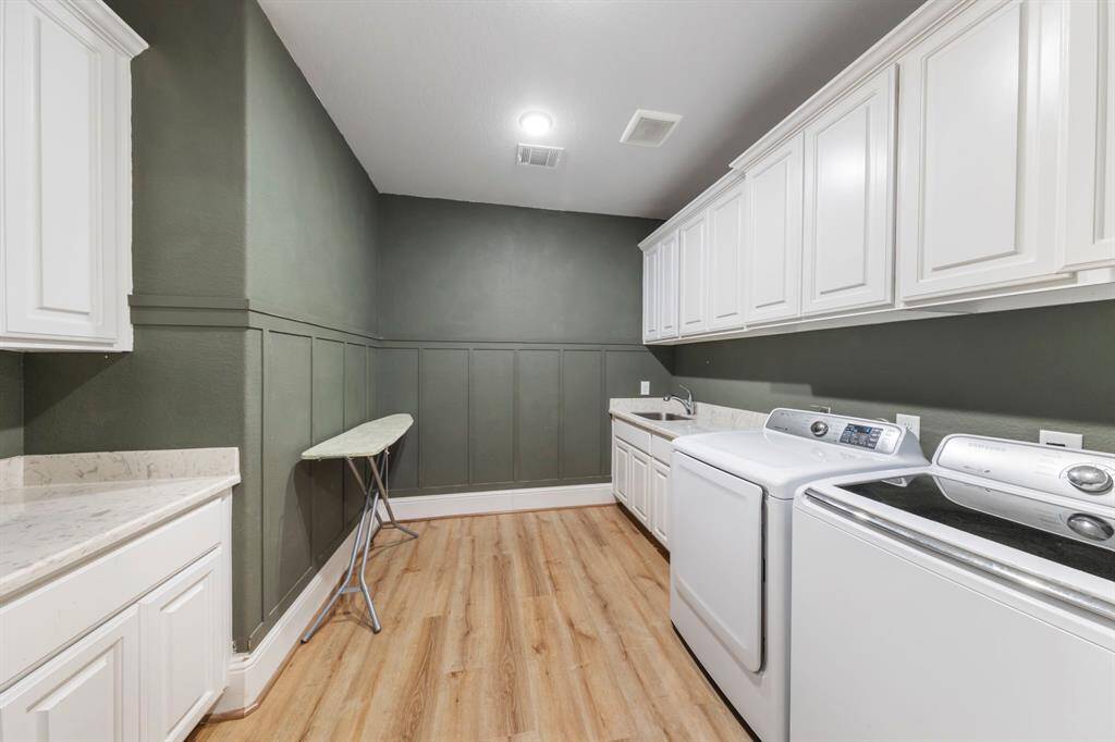 Spacious utility room offering functionality and style, with ample storage, a folding counter, and a convenient sink.