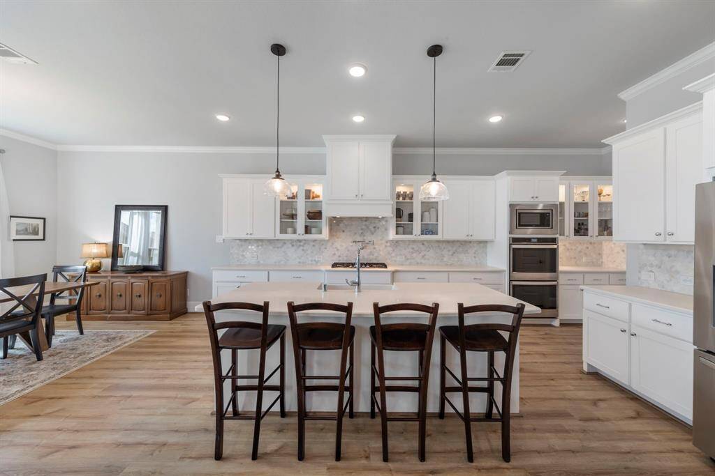 Gourmet kitchen features a pot filler over the gas range, double ovens, ample counter space, and abundant cabinet storage. Timeless white cabinetry creates a bright, open feel, seamlessly connecting to the spacious breakfast room.