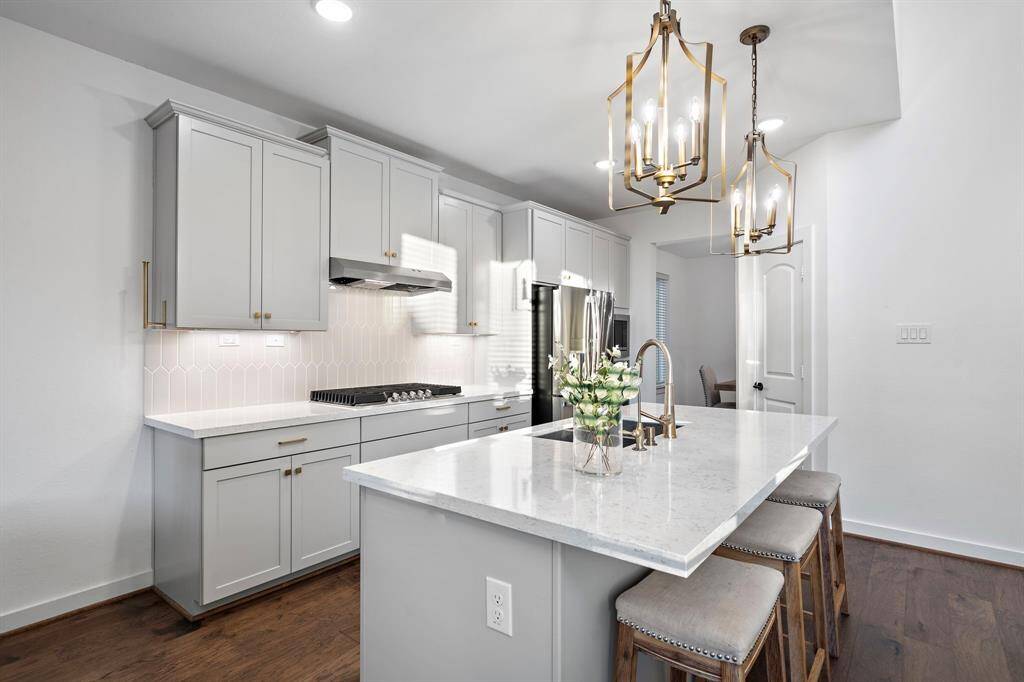 The sleek kitchen features stunning quartz countertops and a gas range, complemented by stainless steel appliances for a touch of contemporary flair. The island offers convenient seating, perfectly blending style and functionality while seamlessly connecting to the dining area for ease of entertaining.