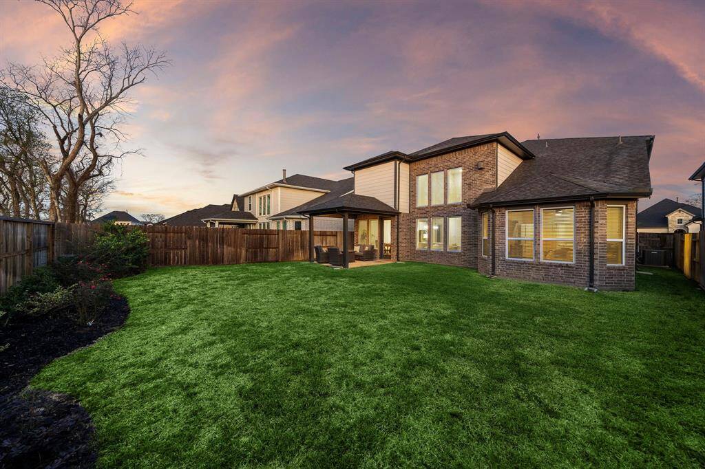 The expansive backyard features a vibrant, lush lawn and a privacy fence, creating a peaceful outdoor retreat. This tranquil space is the perfect extension of the home, ideal for relaxation, entertaining, or play.
