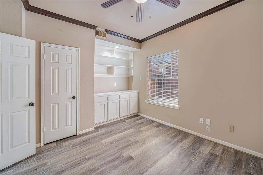 This home offers two bedrooms downstairs. One being this secondary bedroom currently being used as a home office with built-ins, and decorative crown molding!