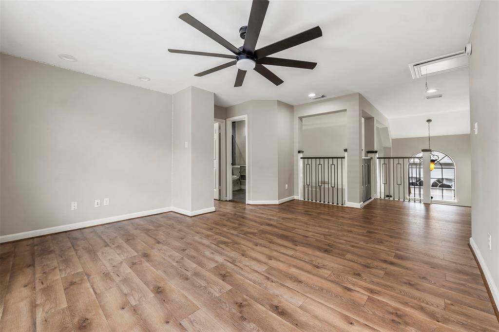A gorgeous wrought iron railing outlines the staircase that leads up to this game room with pretty laminate flooring!