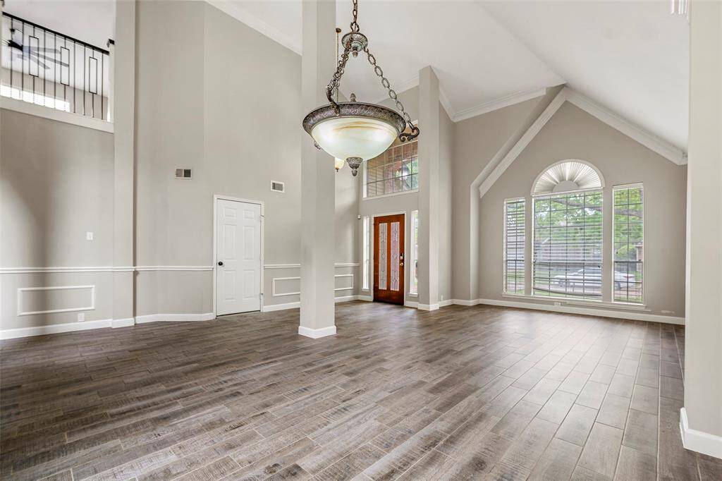 A bright open and welcoming living room as you walk through the front door with crown molding and windows allowing natural light to flow through the space..