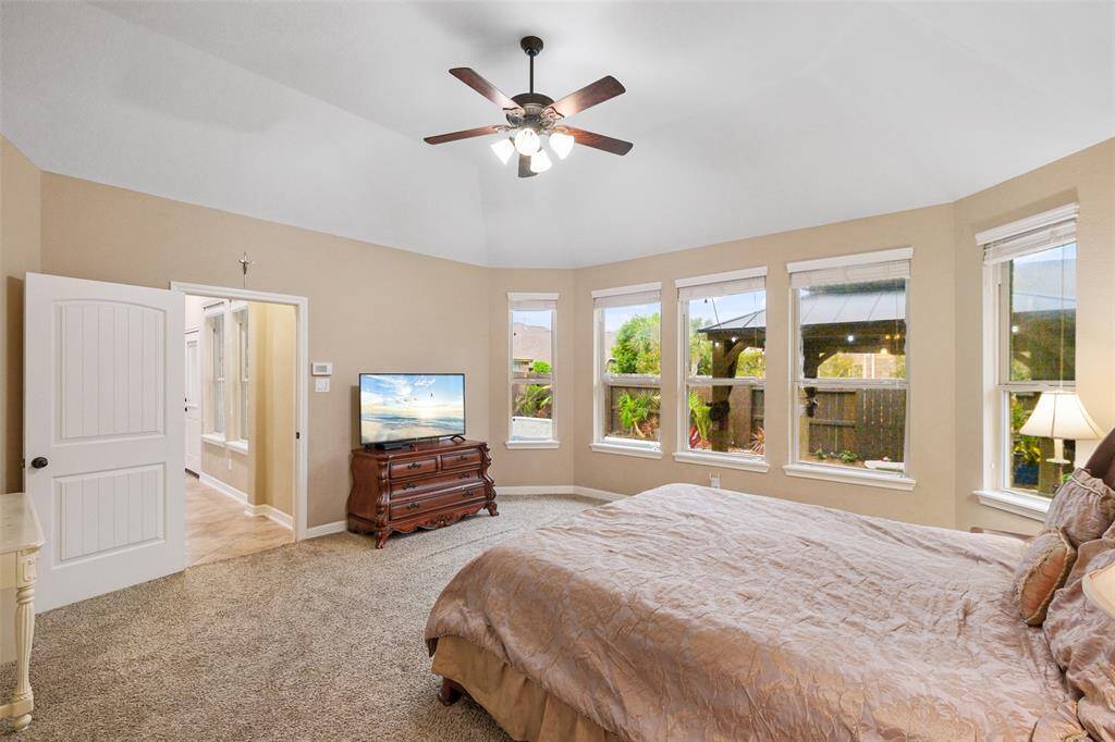 Wake up to sunshine and palm trees! This generously sized primary bedroom offers a wall of windows overlooking your sparkling pool and lush backyard oasis.