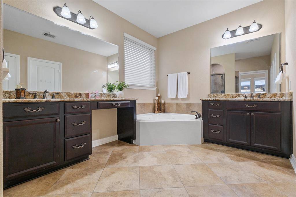 Dual vanities with granite countertops, rich espresso cabinetry, and a soaking tub offer a spa-like escape—plus upgraded Moen bronze fixtures and Aqua Bliss filtered showerheads for the full experience.