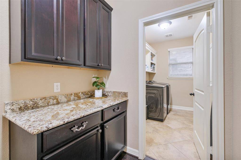 Just off the garage entry, this smartly placed drop zone features granite countertops and rich cabinetry—perfect for stashing bags, keys, or daily essentials. Continue into the laundry room, where the beautiful tile floors and built-in storage keep things tidy and stylish.