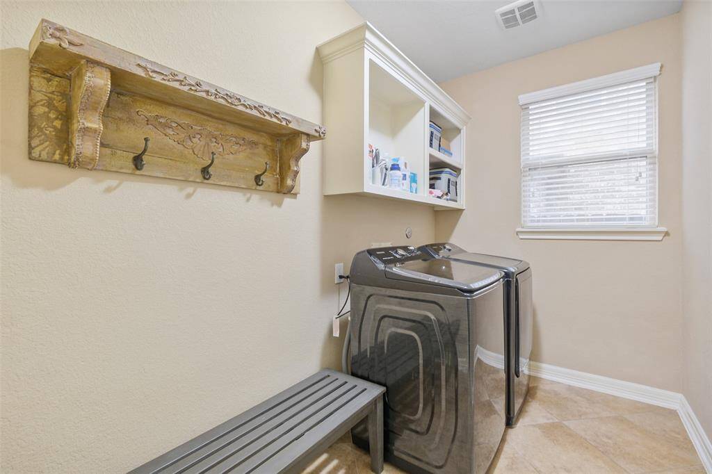 The laundry room is both practical and pretty, with upgraded appliances, shelving, and plenty of natural light.