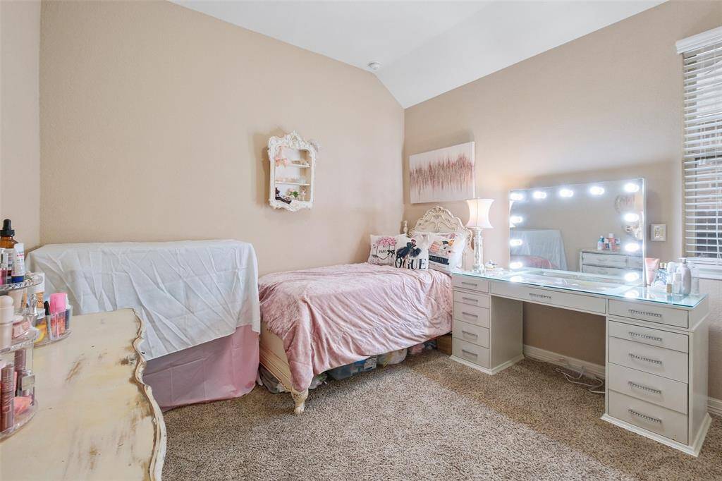 This charming bedroom is full of personality, featuring plush carpet, high ceilings, and space for both rest and creativity.