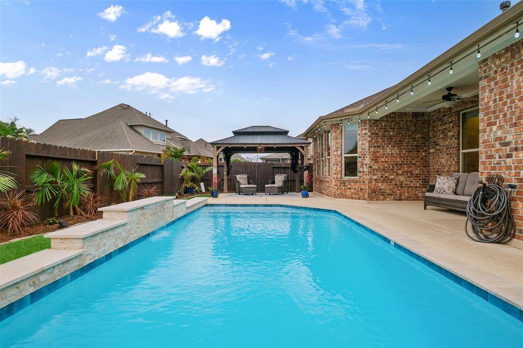 Whether you're throwing a pool party or enjoying a quiet evening, the extended patio space—with café string lights and a ceiling fan—is the ultimate hangout spot.