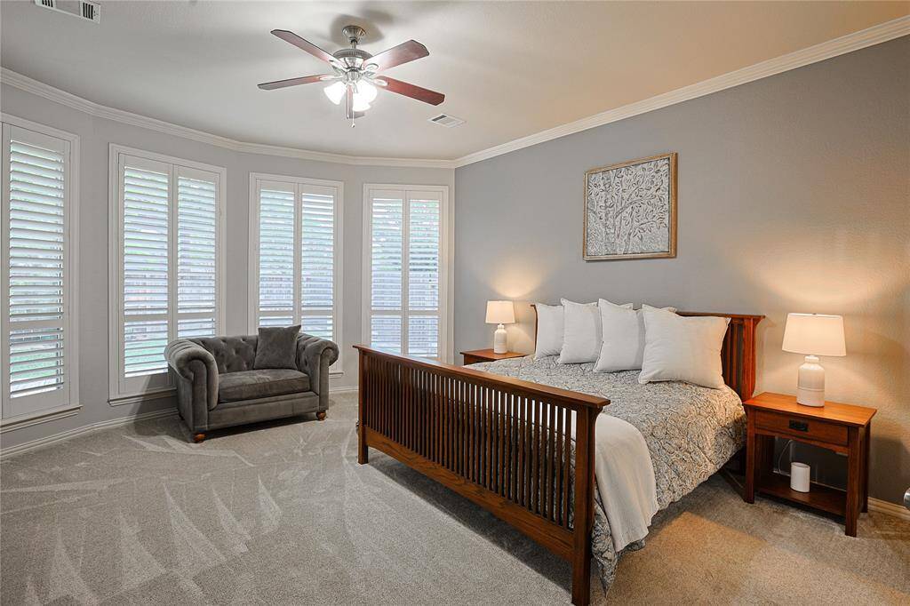 Expansive primary suite with plantation shutters, crown molding and natural light