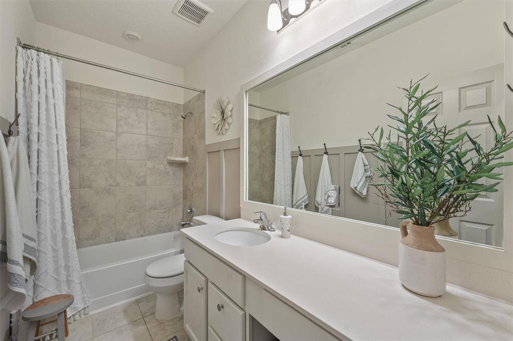 Secondary bathroom featuring a single-sink vanity, ample counter space and a tub/shower combo.