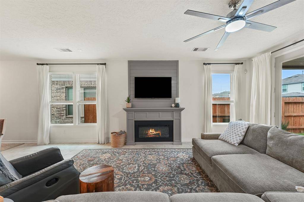 Inviting living room features a stylish accent wall that highlights the fireplace area, adding warmth and character to the space. The current electric fireplace, though not built-in, complements the room beautifully and creates a cozy focal point. If desired, the seller is open to negotiating it as part of the sale.