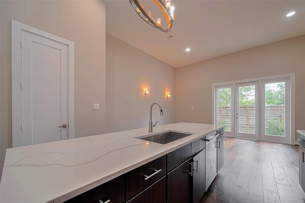 Across from the gas range, the kitchen island features a deep, farmhouse-style stainless steel sink with no divider, ideal for soaking large baking sheets or cookware like crockpots. A convenient vegetable spray nozzle adds functionality. To the right of the sink, you'll find a stainless steel Bosch dishwasher, perfectly positioned for easy cleanup after meals and entertaining.