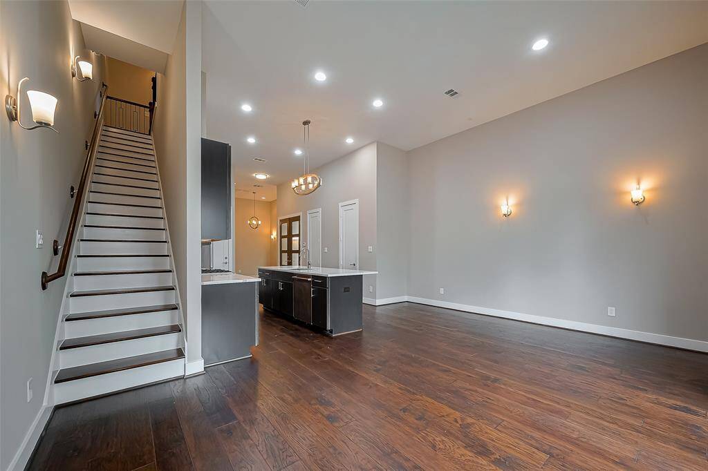 Beautiful engineered wood floors flow throughout the 1st floor, adding an elegant touch to the space. The staircase, with its sleek wood treads, leads to the 2nd and 3rd floors. Wall sconces gently illuminate the staircase and hallways, creating a warm and inviting atmosphere on each level of the home.