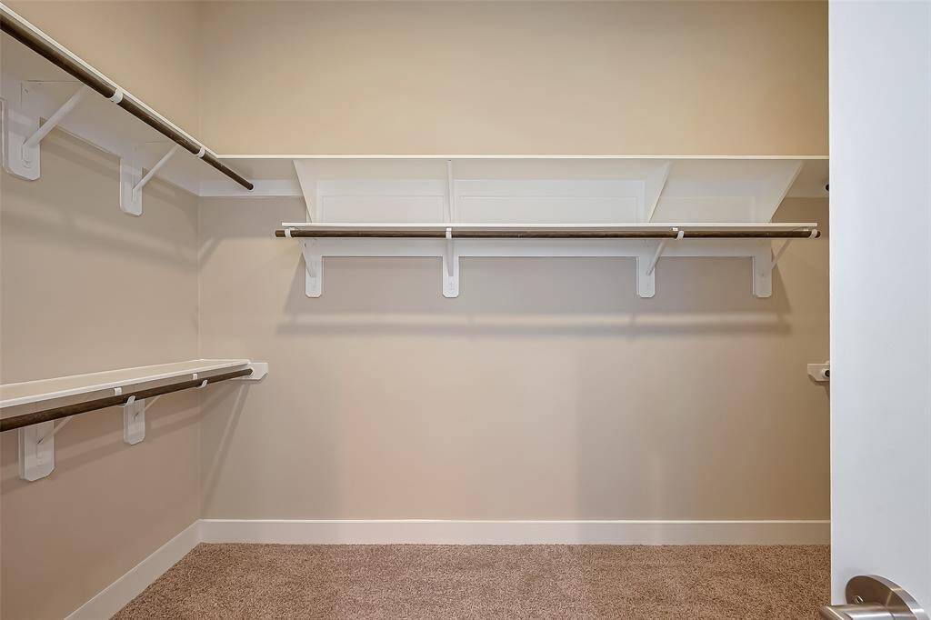 The owner's suite includes a large, lighted walk-in closet measuring 12.4 x 7.5, offering ample space for organization. Multiple clothes rods and storage shelves provide plenty of room for your wardrobe, ensuring everything stays neatly arranged and easily accessible.