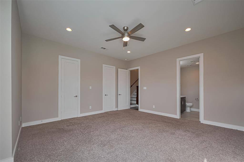 Bedroom #2 features two lighted walk-in closets, each with stacked rods for ample clothes storage. The thoughtful design ensures plenty of space for organization. A doorway on the right leads to the private ensuite bathroom, providing added convenience and privacy.